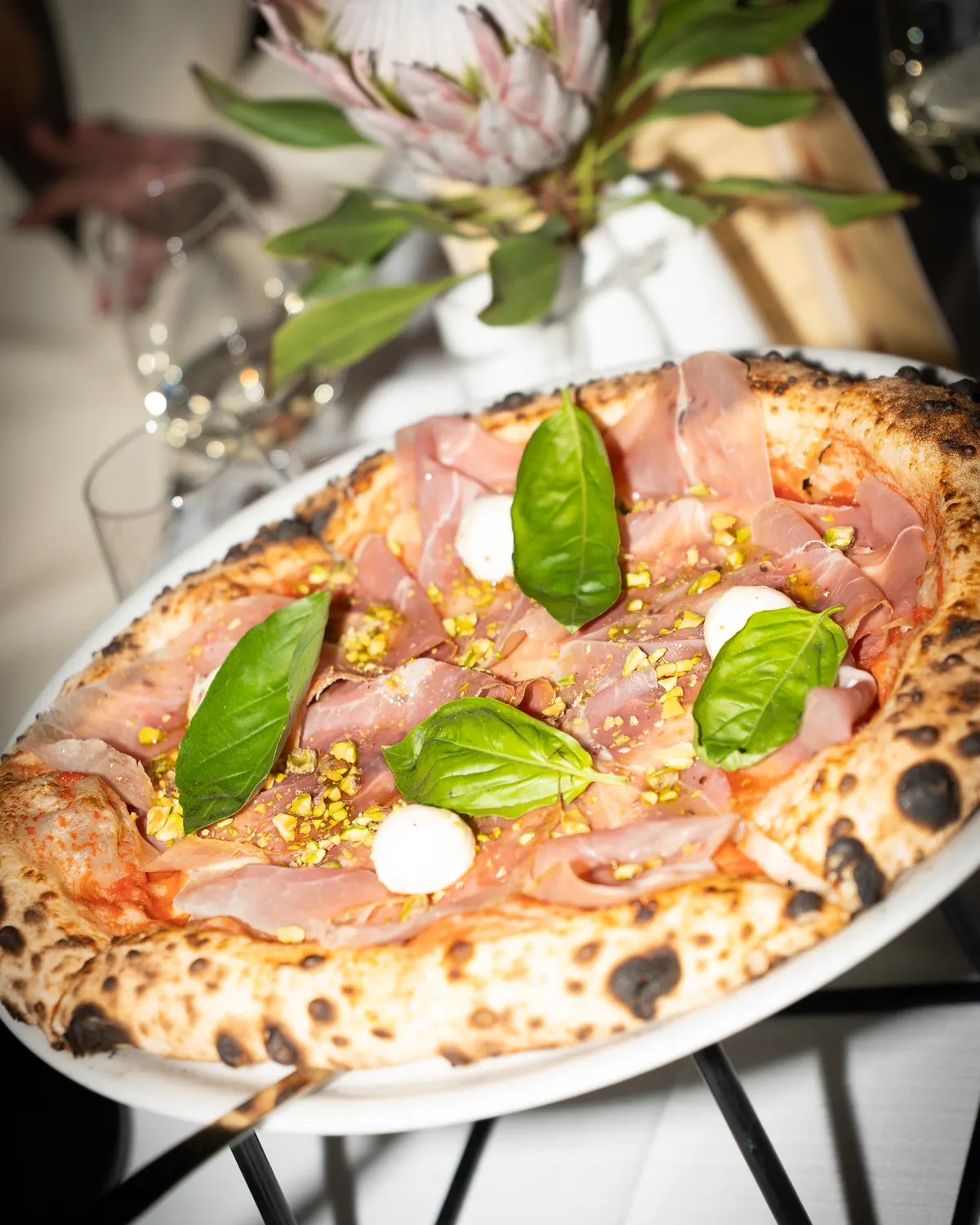 Pizza with prosciutto, basil and pistachios